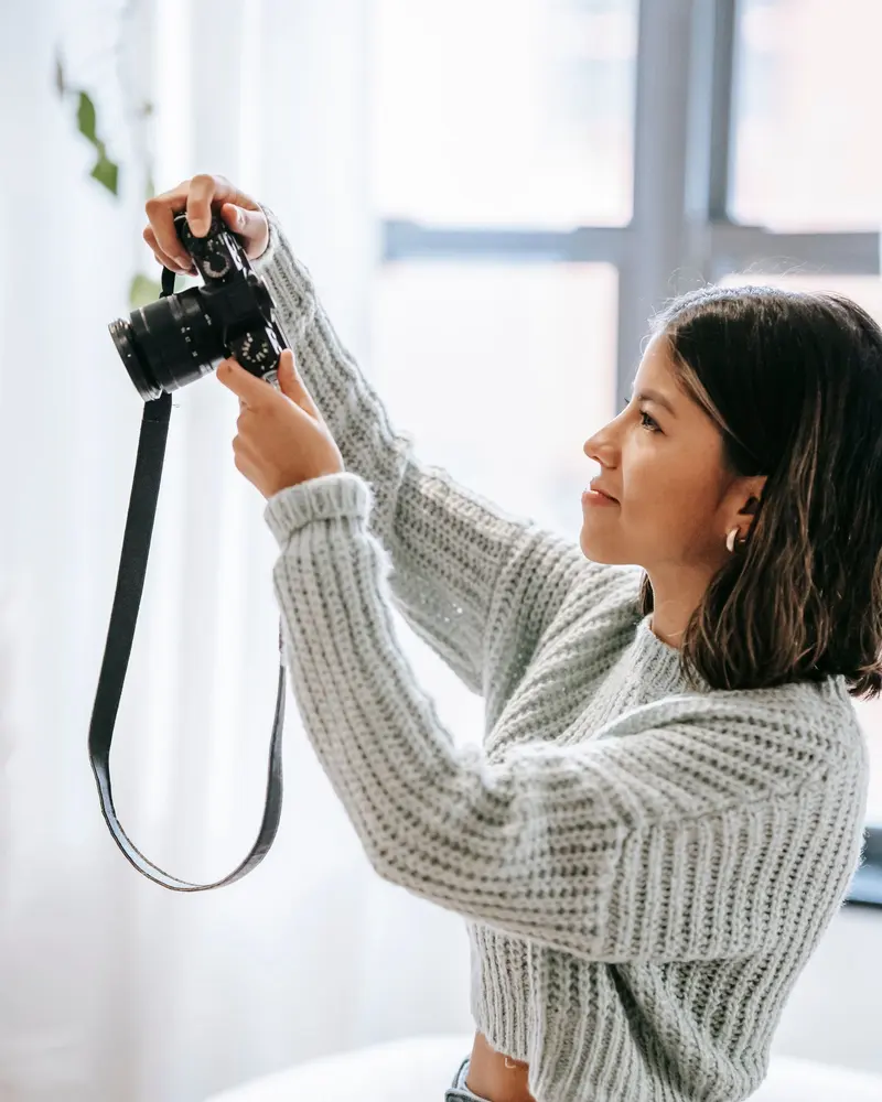 Fotograf som riktar kameran mot ett fönster i ett ljust hem